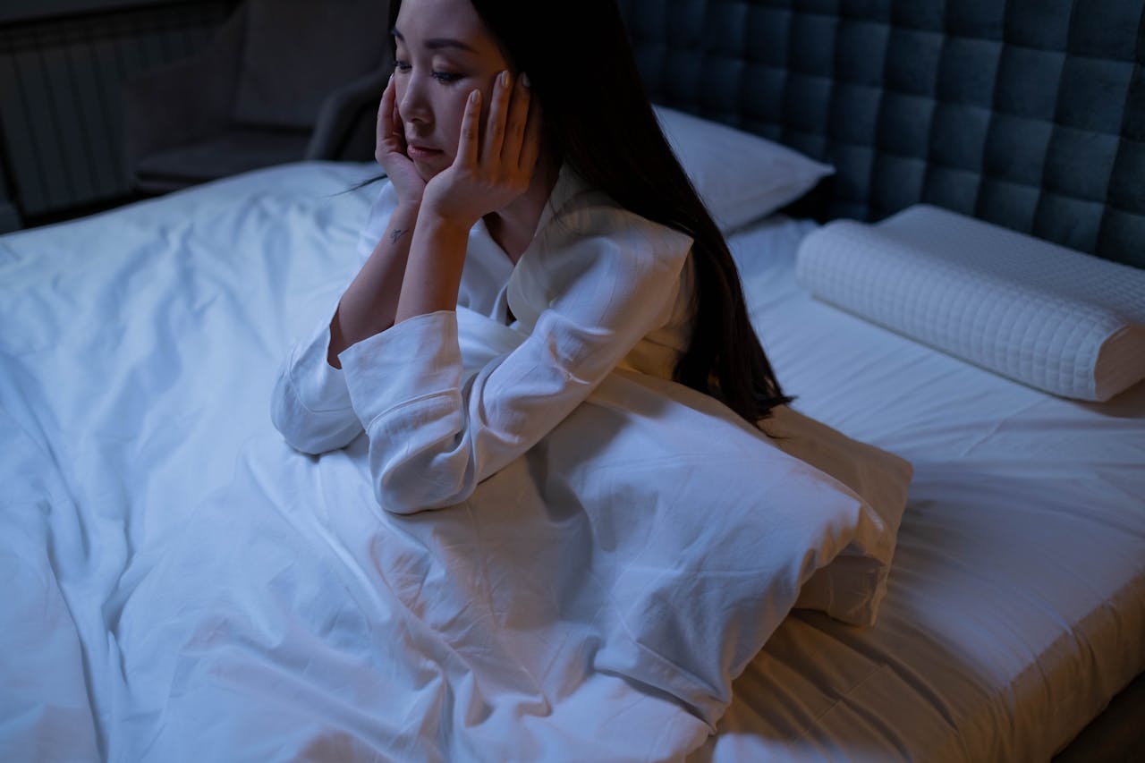 Mujer despierta en la cama con expresión de cansancio, representando los efectos del insomnio crónico en la calidad del descanso.